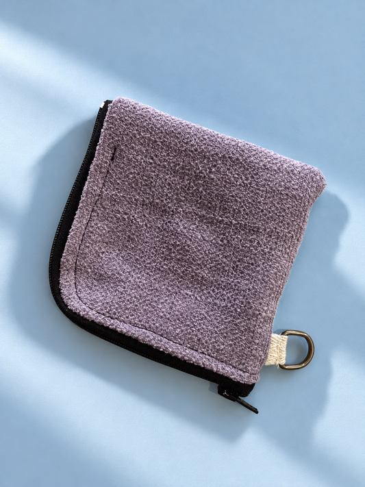 Lavender textured panel of zip pouch with black zipper and gold-tone side ring