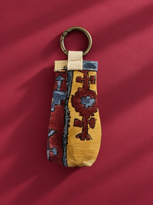 Front of upcycled tapestry keychain pouch in mustard, burgundy, and blue