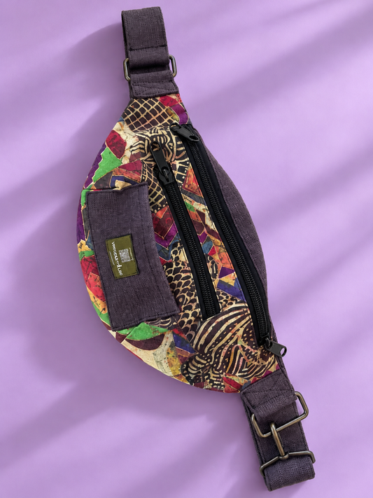 Colorful patchwork sling bag with dark trim on a lavender background