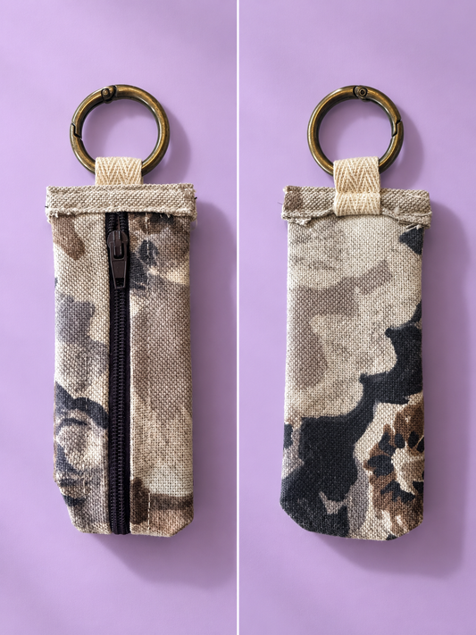 Front and back views of a beige and charcoal camouflage keychain pouch with a black zipper and brass-tone key ring