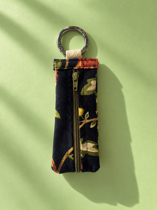 Dark floral tapestry keychain pouch with a zipper and silver-tone metal key ring