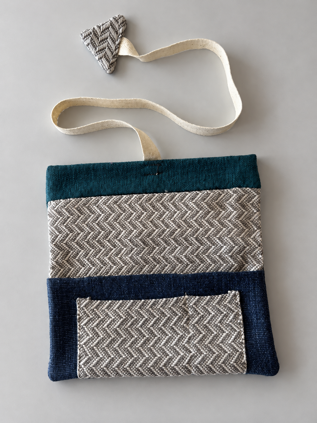 Grey and cream herringbone patchwork pouch with teal top panel, navy lower panel and herringbone pocket