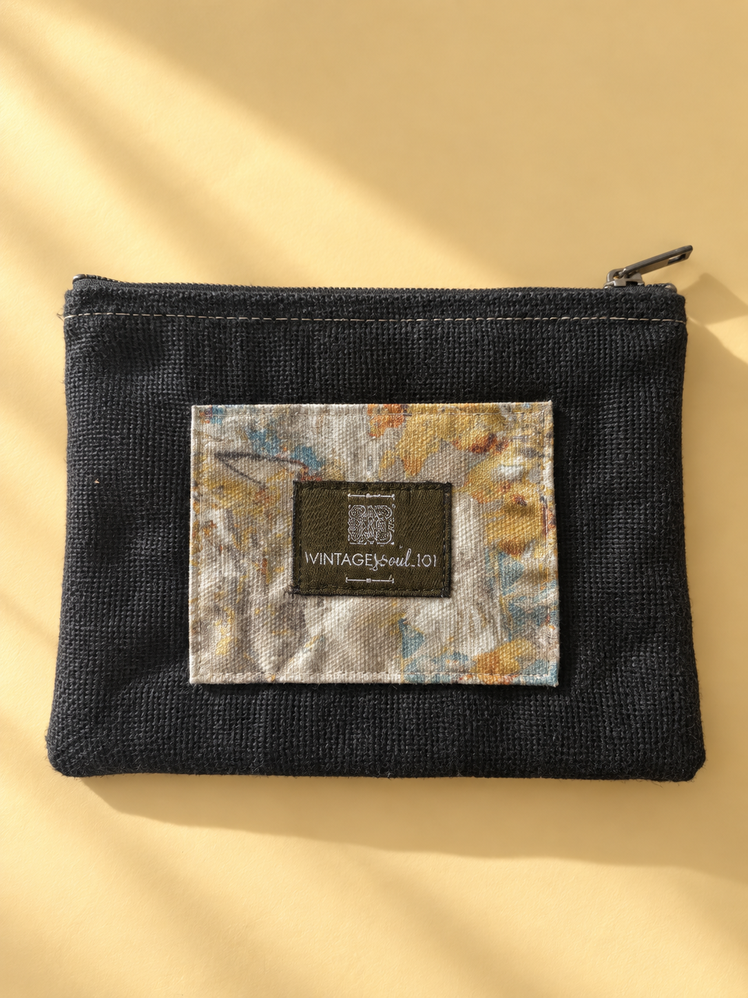 Charcoal mini-pouch with a patterned panel, Vintagesoul 101 label, and top zipper