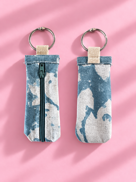 Front and back views of a soft blue and cream abstract keychain pouch with a zipper and silver-tone key ring