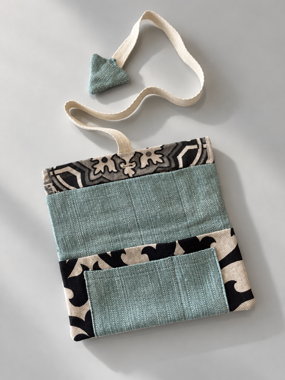 Teal patchwork side of pouch with black and cream patterned panels and teal pocket