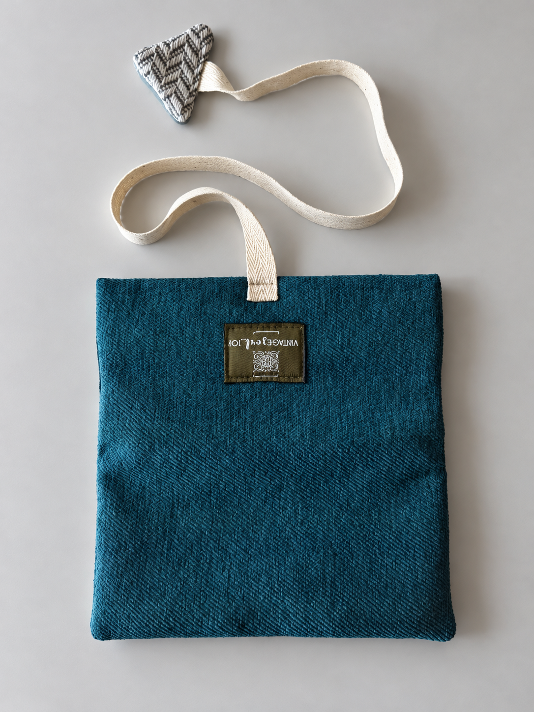 Teal textured pouch with cream woven strap and herringbone triangular detail