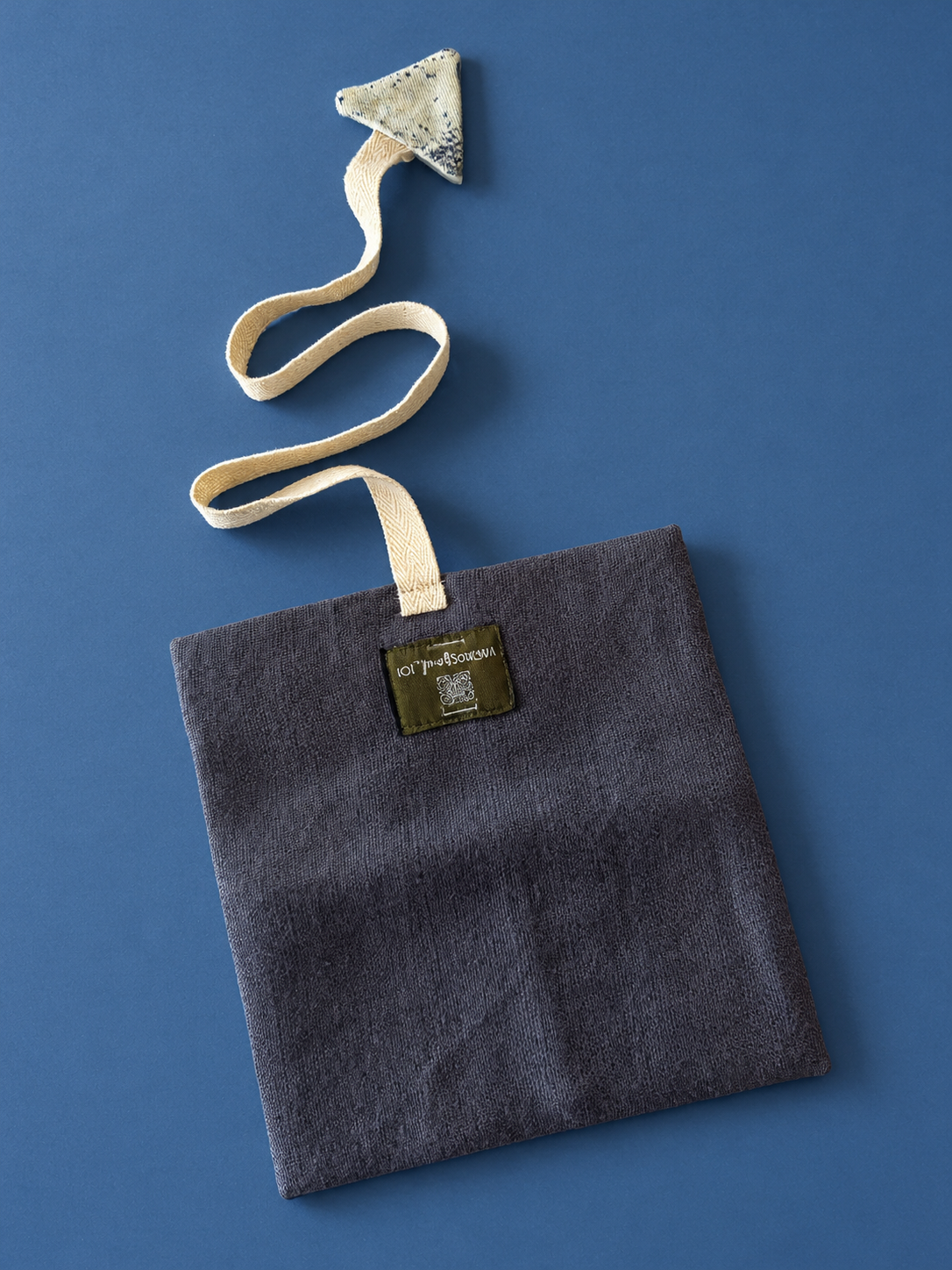 Charcoal textured pouch with cream woven strap and patterned triangular detail